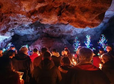 People holding candles in a cave at Carols in the Cave at Kents Cavern